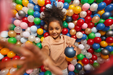 Portrait of African little girl playing with colored balls in the pool