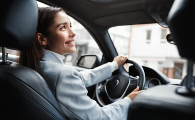 Happy elegant woman driver looking at person sitting in her car, pick up passenger. Businesswoman...