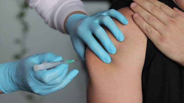 Close up shot of a nurse injecting vaccine into patient's arm then cleaning it with sterile gauze