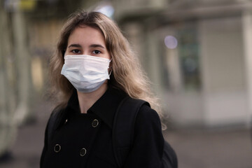 girl at the train station wearing a medical mask