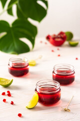 Red alcoholic shots on white background , small jars with liquor and grenadine with lime