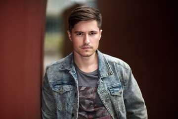 Obraz premium Handsome man posing near a wall wearing jeans jacket