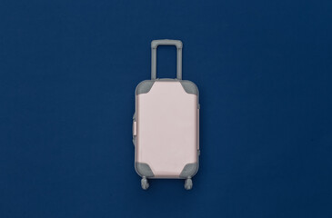 Travel concept. Mini plastic travel suitcase on classic blue background. Minimal style. Top view, flat lay