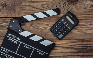 Film clapper board with calculator on wooden background. Cinema industry, entertainment. Top view