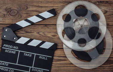 Movie clapper board and film reel on wooden background. Cinema industry, entertainment. Top view