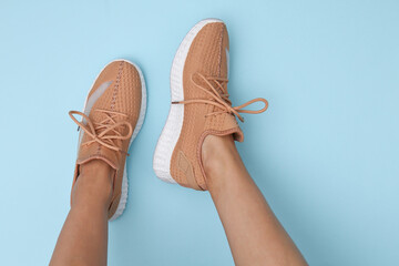 Female feet in trendy sports shoes on blue background. Top view. Flat lay