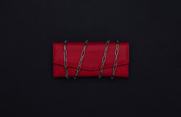 Leather wallet wrapped in a steel chain on black background.