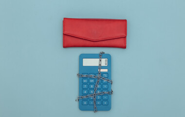 Calculator wrapped in steel chain and wallet on blue background. Top view
