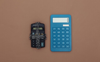 Calculators wrapped in steel chain on a brown background. Top view