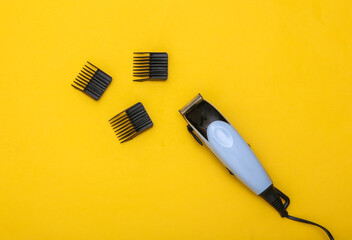 Hair clipper with attachments on a yellow background. Top view
