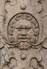 Ancient carved stone face in a flat wall commonly revered in ancient cultures.