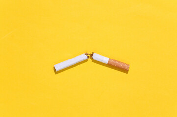 One Broken cigarette on yellow bright background. Quitting smoking