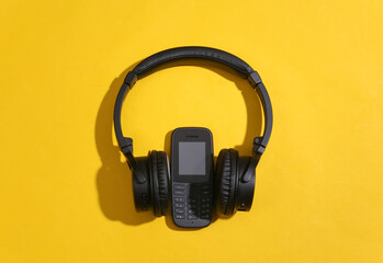 Push-button telephone with stereo headphones on a yellow background. Top view