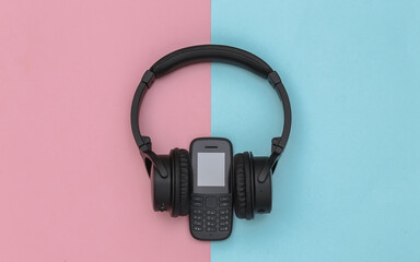 Push-button telephone with stereo headphones on pink blue background. Top view