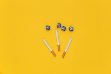Cigarettes with dice on yellow background