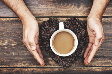 Fototapeta na wymiar Young person hand holding coffee on wooden table.