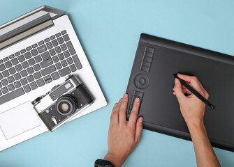 Woman photographer or retoucher working with graphic tablet camera and laptop on blue background