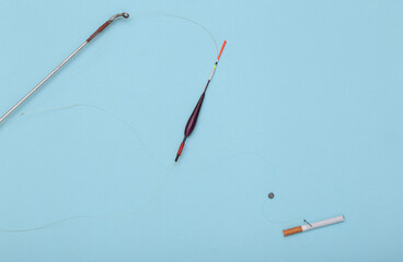 Nicotine addiction concept. Cigarette on the hook of a fishing rod on a blue background