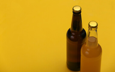 Bottle of light and dark beer on yellow background.