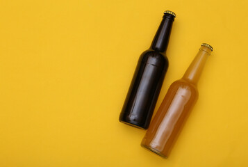 Bottle of light and dark beer on yellow background. Copy space