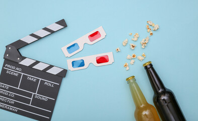 Movie time. Beer bottles, movie clapper, 3d glasses and popcorn on blue background. Top view. Flat lay