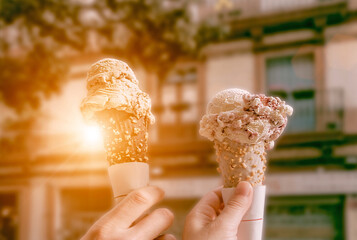 A couple holding ice cream scoops in cones with chocolate, vanilla and strawberry. Tourists in Europe on a hot summer day enjoying ice cream cones. - 392495601