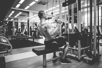 Fitness muscular man with naked torso working out in lat pulldown exercise machine in gym
