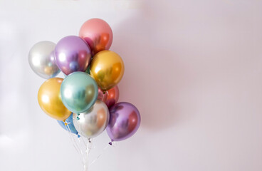 ten helium balloons in metallic colors on a mauve background, copy space on the right © Javier
