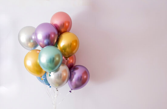 ten helium balloons in metallic colors on a mauve background, copy space on the right
