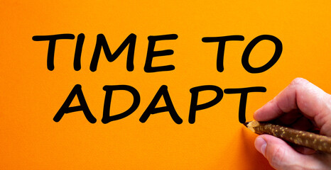 Hand writing 'time to adapt', isolated on beautiful orange background. Business concept. Copy space.