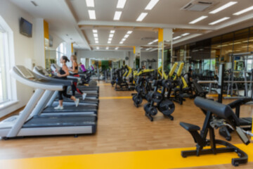 Fototapeta na wymiar Blurred image of a modern gym with people exercising. Sports background. Gym interior