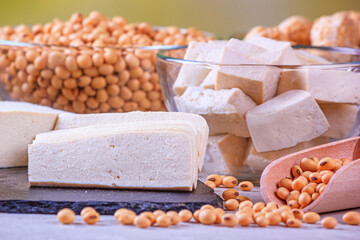 Tofu, also known as bean curd, diced on the black surface of the slate stone, closeup with...