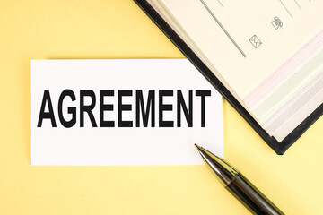 AGREEMENT, text on white paper on yellow background