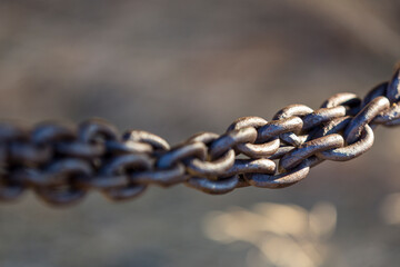 Two chains twisted together into a barrier shallow depth of field against an out of focus grey background
