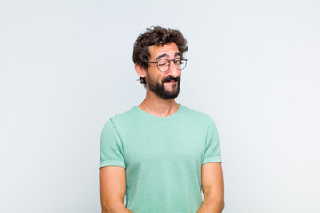 young bearded man looking happy and friendly, smiling and winking an eye at you with a positive...