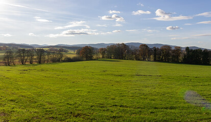 Czech autumn landscape. Meadow with trees and distant hill at day time