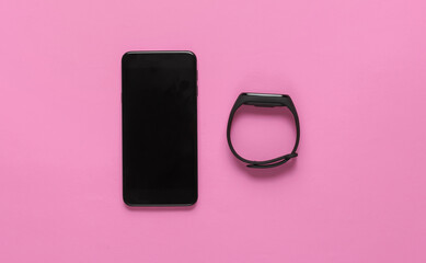 Smartphone and smart bracelet on pink background. Modern gadgets. Top view. Minimalism
