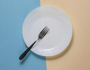 Empty plate with a fork on yellow blue pastel background. Studio shot. Restaurant food concept.