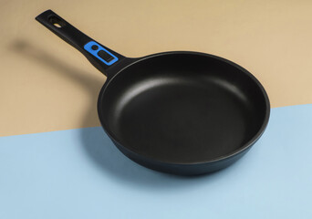 Frying pan with a non-stick coating on a blue-yellow pastel background. Cooking minimalism concept