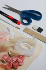 Needlework accessories. Dried flowers and ribbons for crafts. Tools for creativity. On a white tabletop.