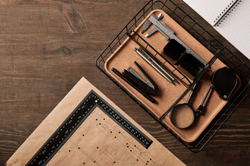 Overview of office supplies and handtools in basket, pens, ruler on blueprint