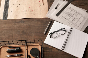 View of supplies and handtools in basket, rulers on blueprints and eyeglasses
