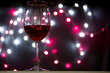 A glass of wine. Against the background of a blur of colored lights of burning garlands.