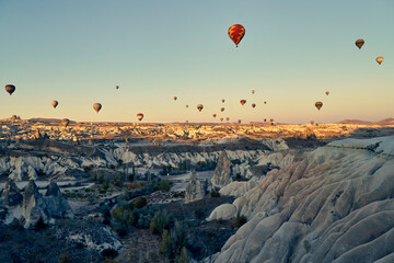 Hot air balloons and Red valley at sunset, Daily take-off of balloons in Cappadocia, on the city of Goreme, Turkey.