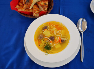 Plate with lagman soup and lavash on blue tablecloth