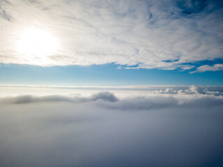 Obraz premium Aerial view. Flying over white clouds during the day in sunny weather.