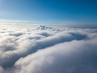 Fototapeta premium Aerial view. Flying over white clouds during the day in sunny weather.