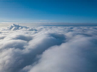 Naklejka na ściany i meble Aerial view. Flying over white clouds during the day in sunny weather.