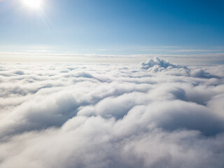 Naklejka premium Aerial view. Flying over white clouds during the day in sunny weather.