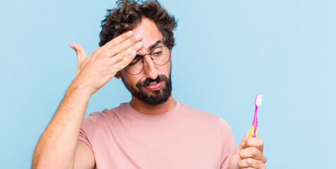 young bearded man looking stressed, tired and frustrated, drying sweat off forehead, feeling hopeless and exhausted